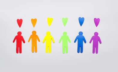 Paper human figures and hearts in colors of LGBT flag on grey background. Valentine's Day celebration