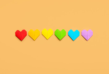 Paper hearts in colors of LGBT flag on beige background. Valentine's Day celebration