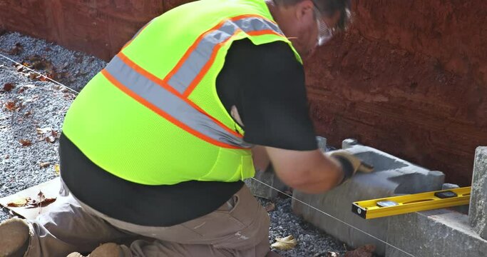 An contractor was installing concrete block after leveling walls on part new retaining wall construction project.