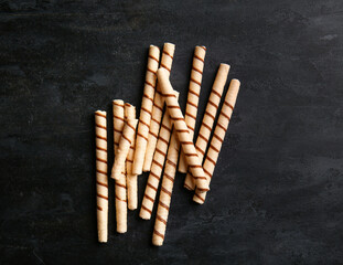 Heap of tasty wafer rolls on black background