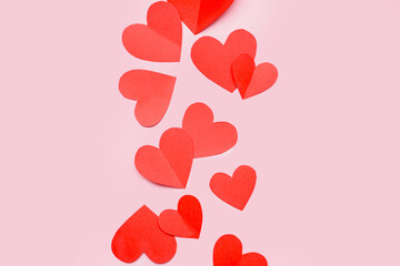 Red paper hearts on pink background. Valentines Day celebration