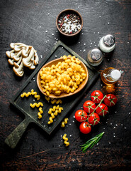Raw pasta in bowl with mushrooms, tomatoes and spices.
