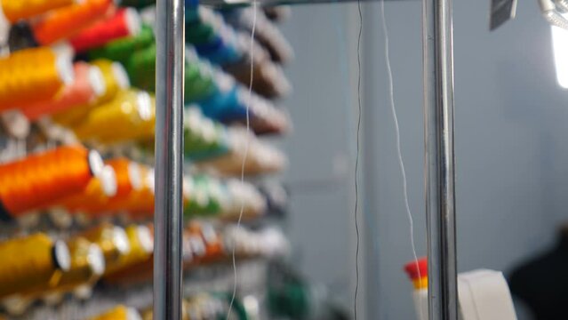 Rows spools of thread of different colors in industrial sewing factory. Textile Industry at Garment Manufacturers. Weaving machine for garment industry. Sewing workshop or tailoring factory. 4 k video