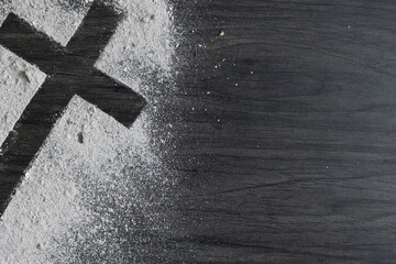 Cross of ashes on a dark wood background with copy space