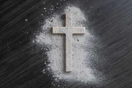 Cross covered with ashes on a dark wood background with copy space