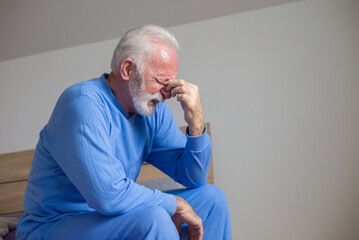 Senior man in pajamas waking with headache in the morning	