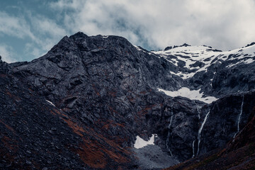 Obraz premium Landscape Shot of Water From Melting Glaciers Above, Cascades off Side of Mountain in New Zealand
