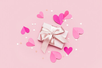 Gift with paper hearts on pink background. Valentines Day celebration
