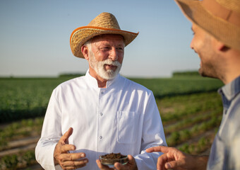 Fototapeta premium Farmer and agronomist talking in field about soil