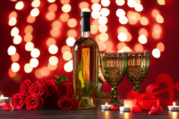 Bottle of wine, rose flowers, glasses and burning candles on black table against blurred lights. Valentine's Day celebration