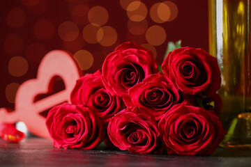 Rose flowers and bottle of wine on black table against blurred lights. Valentine's Day celebration