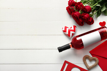 Fototapeta na wymiar Bottle of wine, rose flowers, envelope and hearts on white wooden background. Valentine's Day celebration