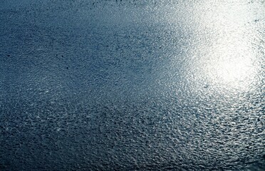 Asphaltierte nasse Straße mit Sonnenspiegelung am Mittag im Winter