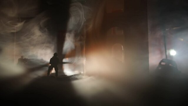 Army sniper with large caliber rifle standing in the fire and smoke. War Concept. Battle scene on war fog sky background, Fighting silhouettes Below Cloudy Skyline at night. City destroyed by war