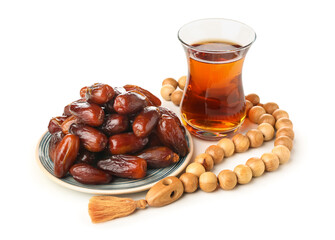 Plate with dried dates, prayer beads and glass of tea for Ramadan on white background