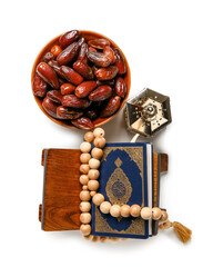 Bowl of dates, prayer beads, Koran and Muslim lantern for Ramadan on white background