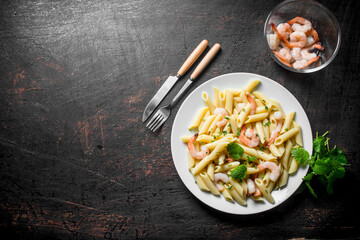 Pasta on a plate and shrimp in a bowl.