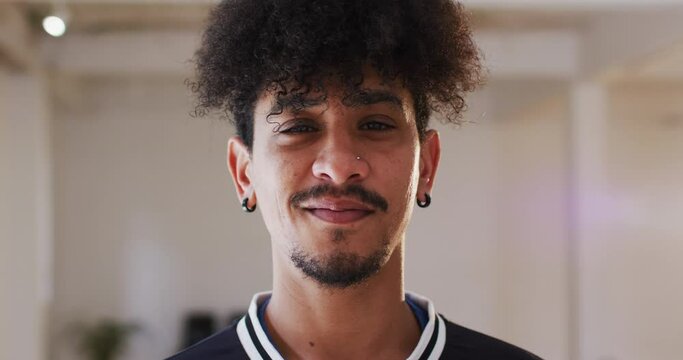 Portrait of happy biracial man looking at camera in dance studio, slow motion