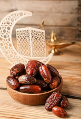 Bowl with dried dates for Ramadan on wooden table, closeup