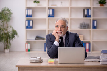 Naklejka premium Old male employee working in the office