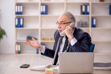 Fototapeta premium Old male employee working in the office