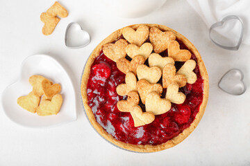 Sweet strawberry pie and heart-shaped plate of cookie hearts for Valentine's day on white background