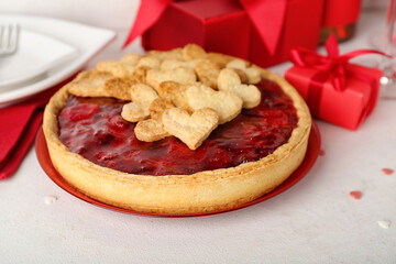 Plate with sweet strawberry pie, cookie hearts and gifts for Valentine's day on white table