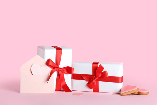 Gift boxes with beautiful bows, envelope and heart-shaped cookies on pink background. Valentine's Day celebration - Powered by Adobe