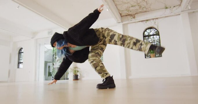 Caucasian female dancer dancing alone and wearing hat in dance studio, slow motion