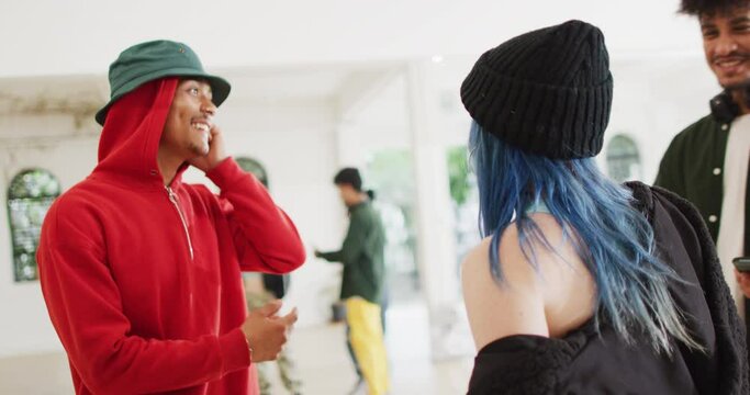 Happy diverse male and female dancers talking and greeting in dance studio, slow motion