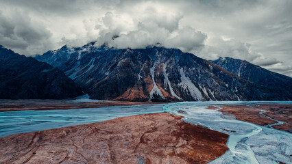Scenic Drone Aerial Landscape Shot of Light Blue Glacial Streams Flowing In Valley Below Massive...