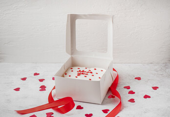Box with tasty bento cake, hearts and ribbon on white table. Valentine's Day celebration