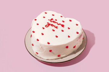 Plate with heart-shaped bento cake on pink background. Valentine's Day celebration