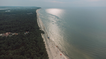 Sand beach with green pines, sea with waves on the Baltic Sea from above