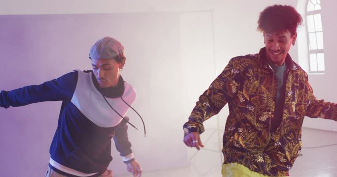 Happy biracial male dancers dancing together in dance studio, slow motion