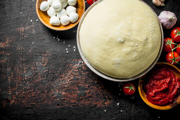 Raw pizza. Dough with tomato paste, mozzarella and cherry tomatoes.