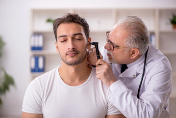 Young male doctor visiting old doctor otolaryngologist