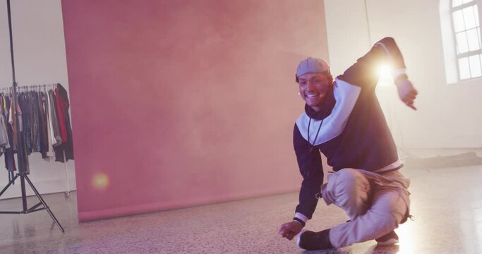 Happy biracial male dancer dancing alone in dance studio, slow motion