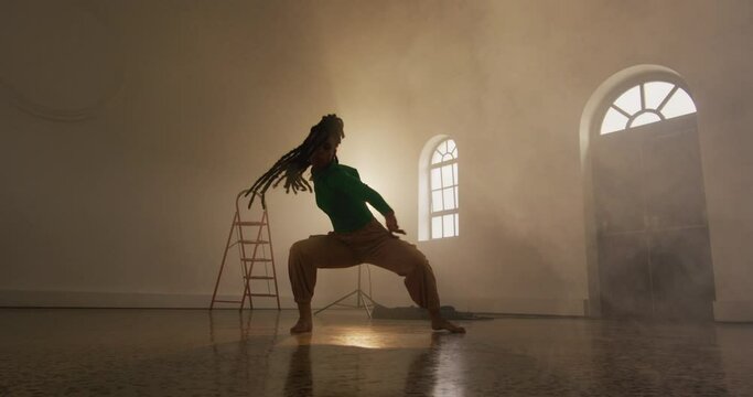 Portrait of biracial female dancer dancing in dance studio, slow motion