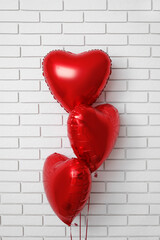 Red balloons for Valentine's Day near white brick wall
