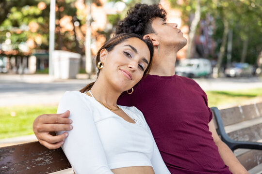 Happy latin couple portrait smiling and relaxing sitting on a bench