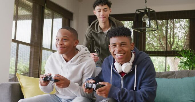 Happy diverse male teenage friends playing video games at home, slow motion