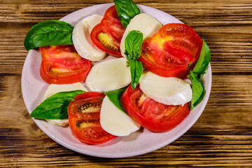 Plate with caprese salad (italian salad with cherry tomatoes, mozzarella cheese and basil leaves)...