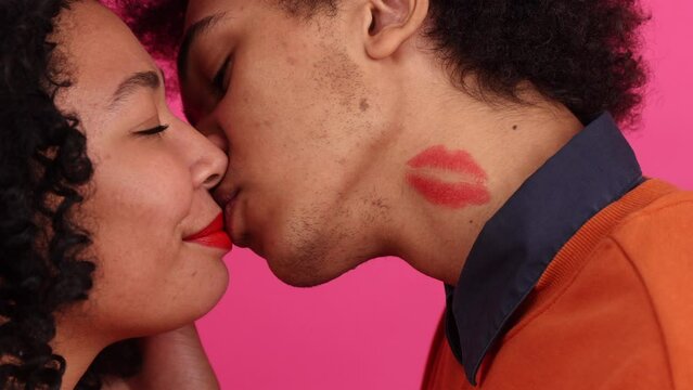 Close-up view of passionate couple kissing and hugging. Portrait of African American, young boyfriend and girlfriend on pink isolated background. High quality 4k footage