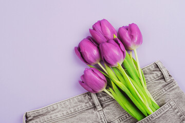 Bouquet of purple tulips in a pocket of gray jeans. Spring holidays concept. Top view, flat lay....