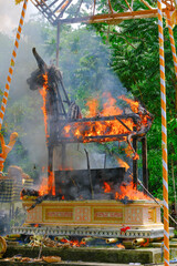 Balinese animal structure burning on concrete pedestal at cremation ceremony