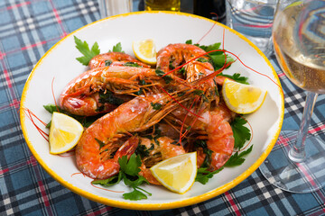 Appetizing grilled shrimps served with parsley and lemon on white plate..