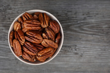 Tasty pecan nuts on grey wooden table, top view. Space for text