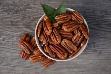Tasty pecan nuts on grey wooden table, flat lay