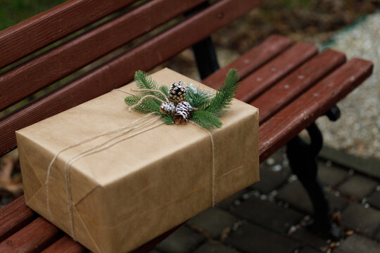 Beautiful gift. New Year's decor with a Cristmas tree and knars. Preparation for the holiday. New Year's gifts on the wooden bench. Close up.